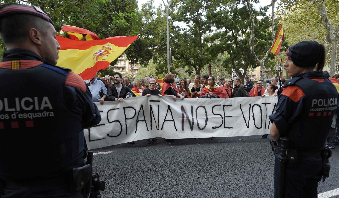 Catalan regional police officers stand guard in front of demonstrators against independence. Photo: AFP