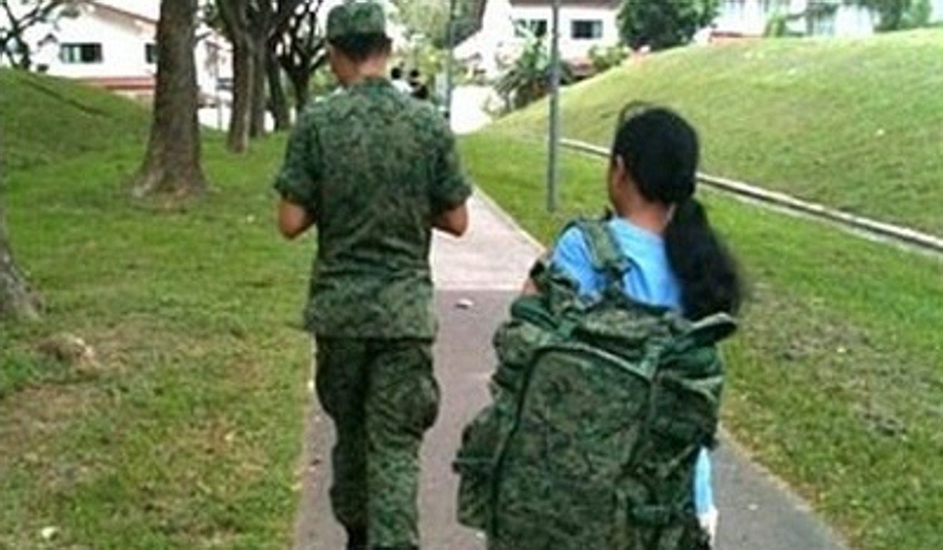 A photograph of a Singaporean military recruit in full uniform with his maid lugging his big backpack for him caused outrage in 2011. Photo: Handout
