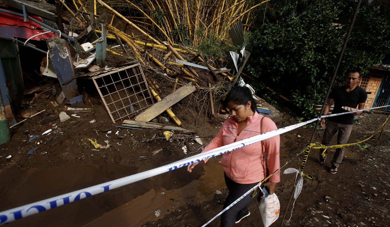 People walk near houses damaged by a mudslide after tropical storm Nate hit San Jose, Costa Rica. Photo: Reuters