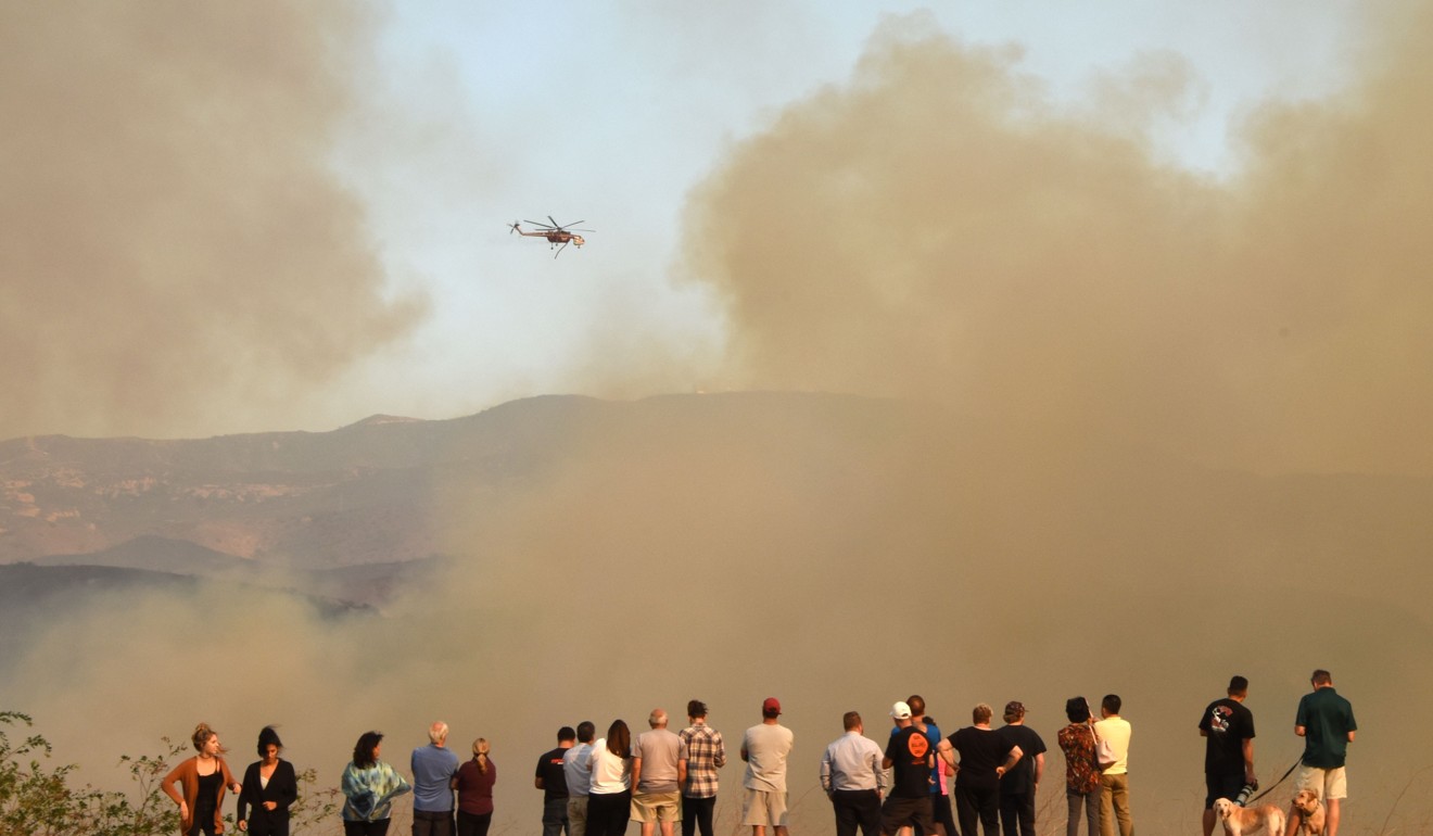People watch water-dropping helicopters amid smoke from the fire in Orange, California. Photo: AFP