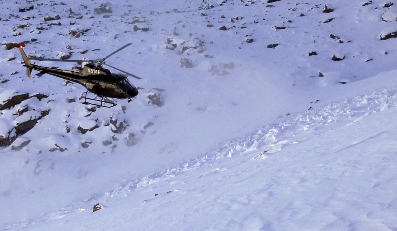A helicopter searches avalanche debris for a missing skier on Imp Peak in the southern Madison Range in southwestern Montana. The body of Inge Perkins was recovered. Photo: AP