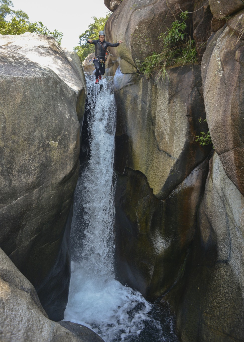 Gordon Hon of Hong Kong Rock Climbing Adventure jumps down a waterfall while on a canyoning expedition in Ma On Shan. Photo: Antony Dickson