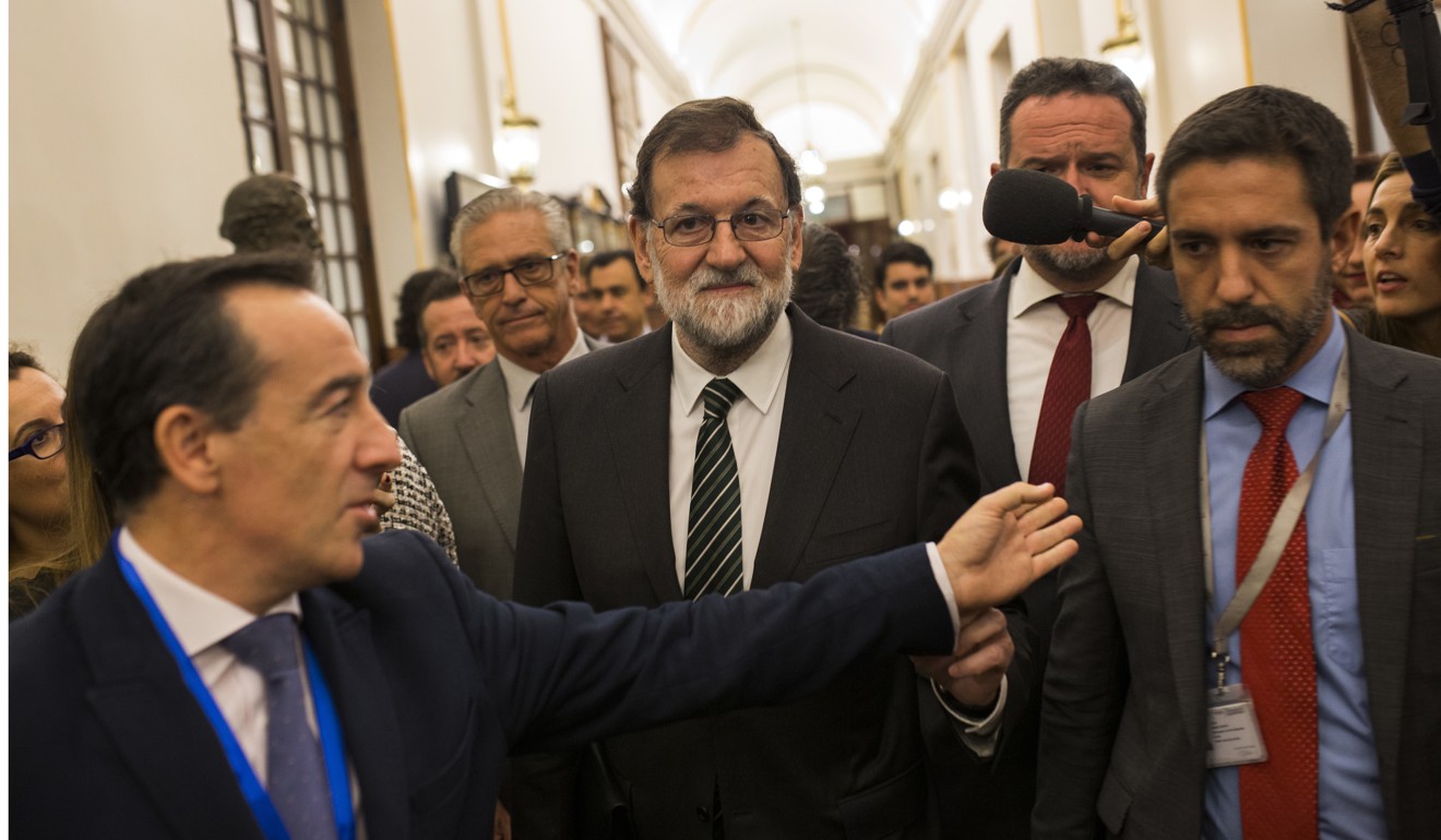 Spain’s Prime Minister Mariano Rajoy (centre) is questioned by journalists as he leaves parliament in Madrid on Wednesday. Photo: AP