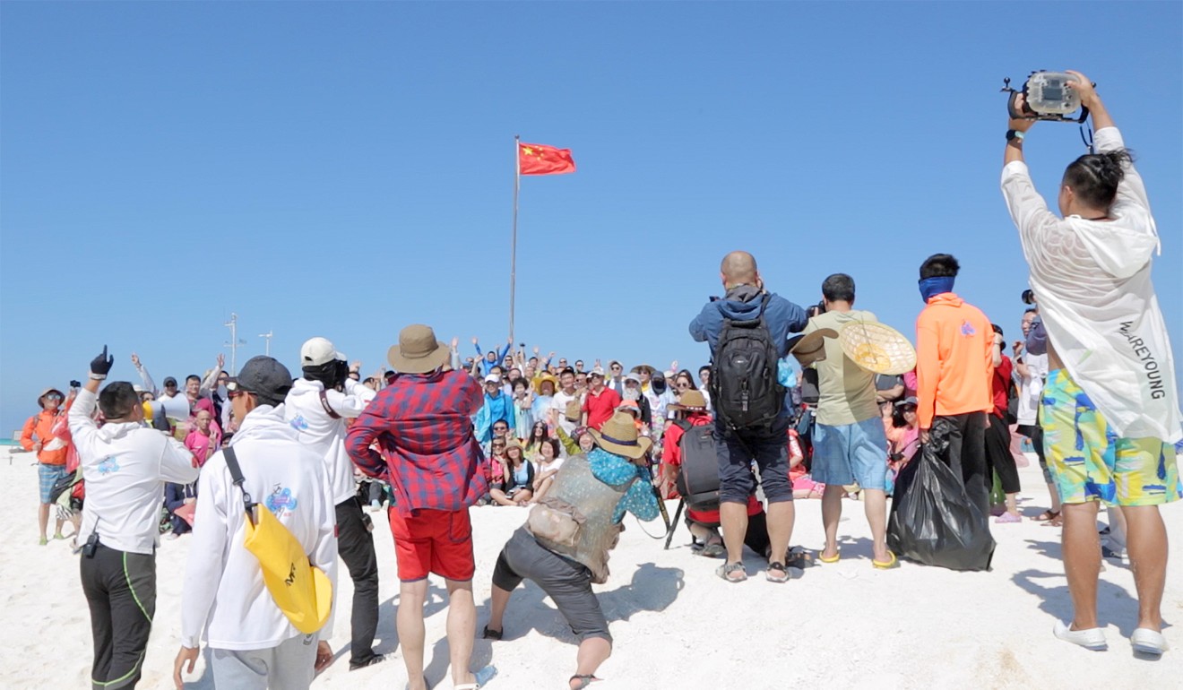 Holidaymakers enjoy a flag-raising ceremony on Quanfu Island in the Paracel. Photo: Liu Zhen