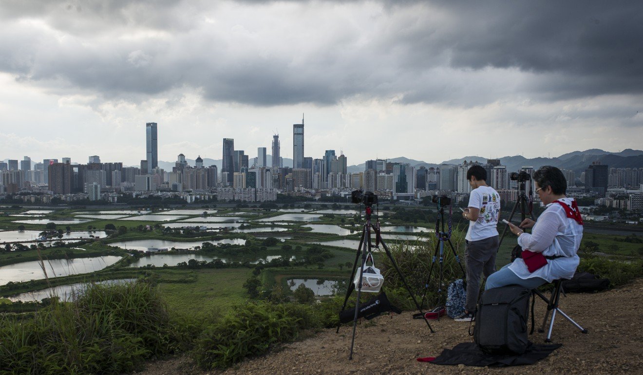 Photographers shoot the Shenzhen-Hong Kong border at dusk in the Ma Tso Lung district of Hong Kong. Shenzhen is pivoting from its legacy as ground zero for China's manufacturing boom to a centre for research, development and production of advanced technology. Photo: Bloomberg