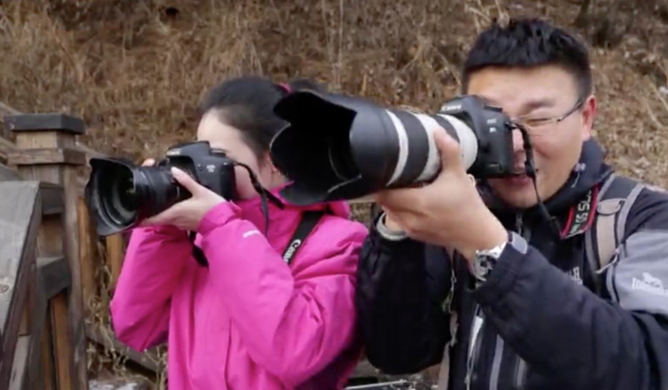Two people take photos of Chinese tanks for a foreign spy in a scene from the video being shown to Chinese secondary school pupils. Photo: Handout