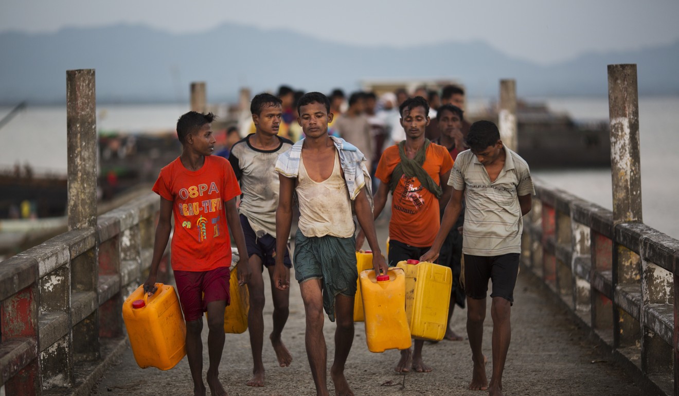 Rohingya Muslims walk down the Shah Porir Dwip dock after using cooking oil drums to float across the Naf river to Bangladesh. Photo: AP