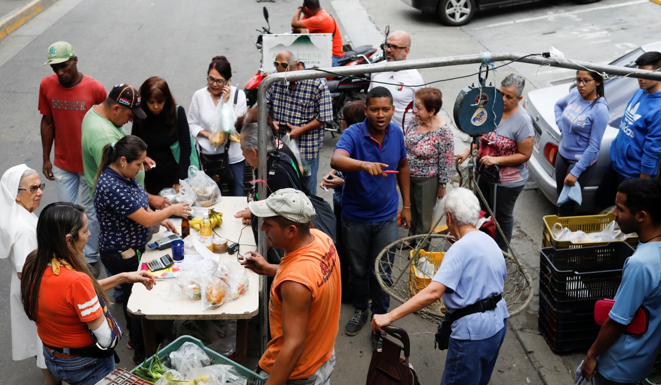 People queue to pay for their fruits and vegetables at a street market in Caracas, Venezuela, as the country lurches into economic recession with a debt default poised to make the situation more difficult. Photo: Reuters