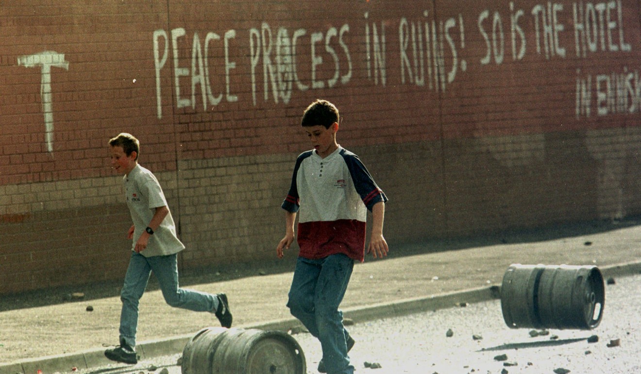 Young boys push beer kegs along a road near graffiti condemning the peace process in East Belfast. Photo: AP