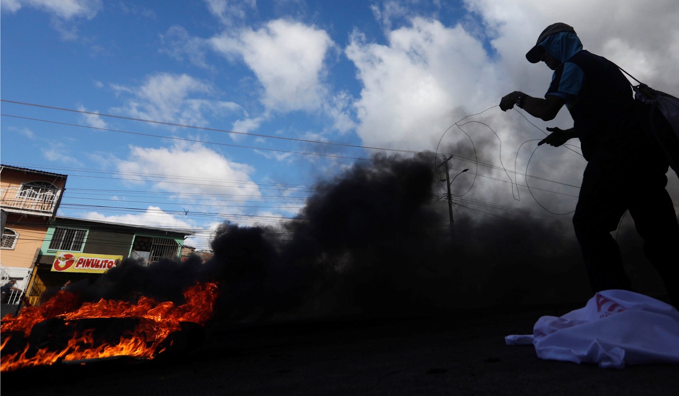 Fires burned on the streets of Honduras as opposition supporters challenged the result of the presidential election, with looters raiding businesses and clashes breaking out between police and demonstrators. Photo: Reuters
