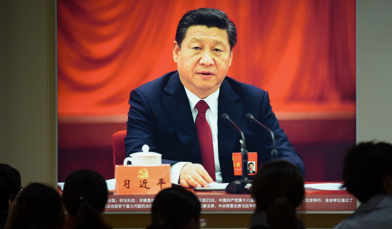 Onlookers view a portrait of Chinese President Xi Jinping at an exhibition showcasing China's progress in the past five years at the Beijing Exhibition Centre in October. As Xi’s crackdown on corruption expands, critics allege that he is attempting to establish total control over the military. Photo: AFP