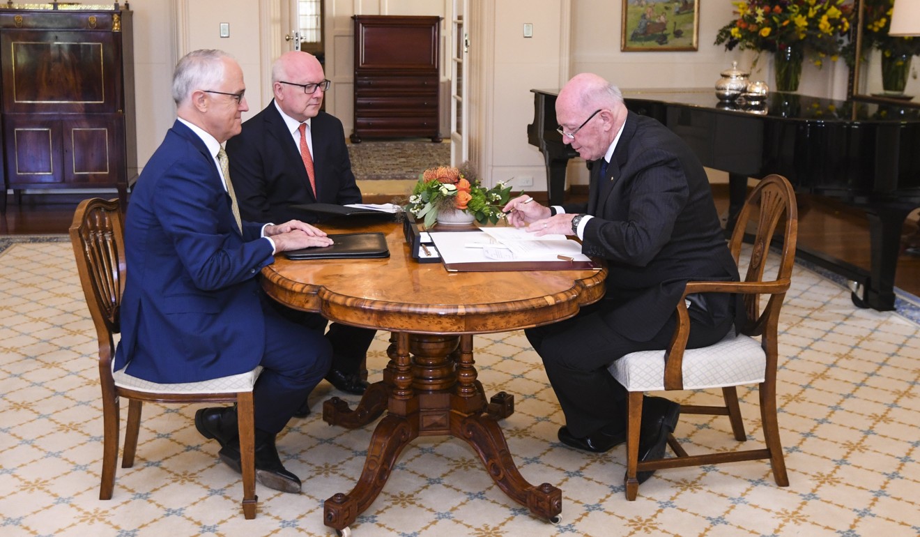 Australian Prime Minister Malcolm Turnbull, Attorney-General George Brandis look on as Australian Governor-General Sir Peter Cosgrove signs the Marriage Amendment Act. Photo: EPA
