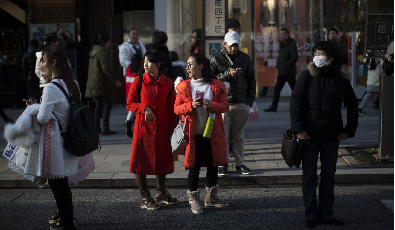Tourists stand in the Ginza district of Tokyo in January. Japan has boomed as a tourist destination in recent years, reaching its goal of 20 million tourists by 2020 five years early, and now targeting the goal of 40 million tourists in the year 2020. Photo: Bloomberg