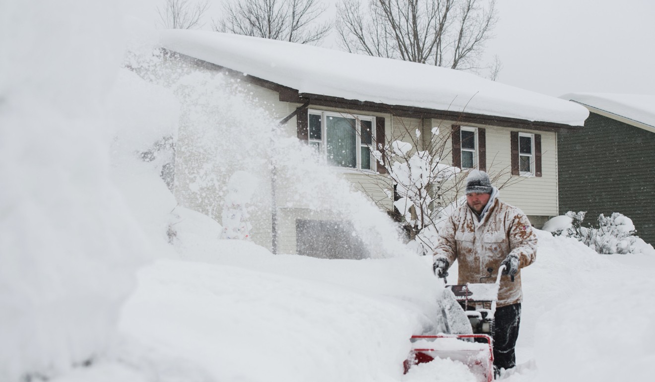 Thomas Berry removes snow from the sidewalk in front of his home after two days of record-breaking snowfall in Erie. Photo: Reuters