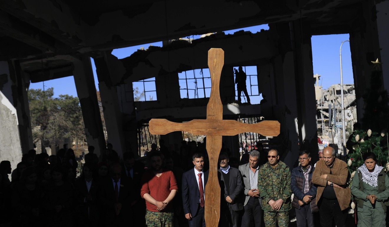 Members of the Syriac Military Council (SMC) and members and leaderships of the Arab-Kurdish SDF (Syrian Democratic Forces) take part in a Christmas celebration at the heavily damaged Armenian Catholic Church of the Martyrs in Raqqa on Tuesday. Photo: AFP