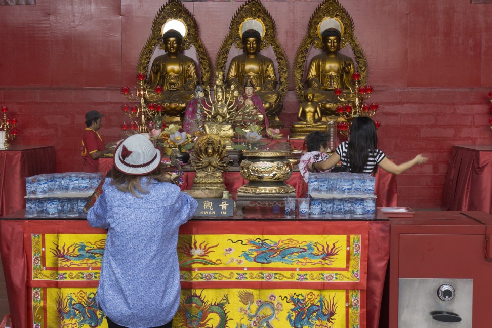 Worshippers pray before statues of Buddha in a temporary prayer hall near the Dharma Bhakti temple. Photo: Nivell Radya