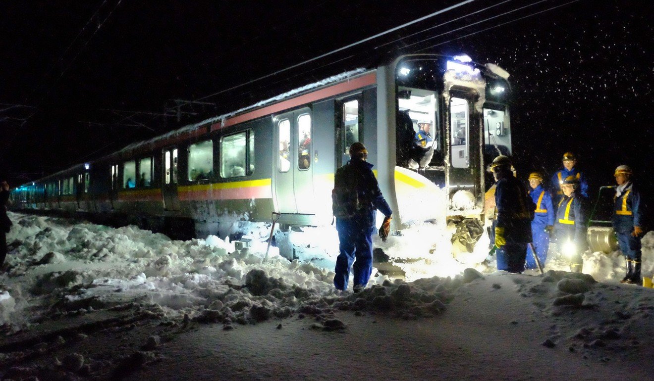 Workers remove snow around a train with hundreds of passengers stranded on board. Photo: Kyoto
