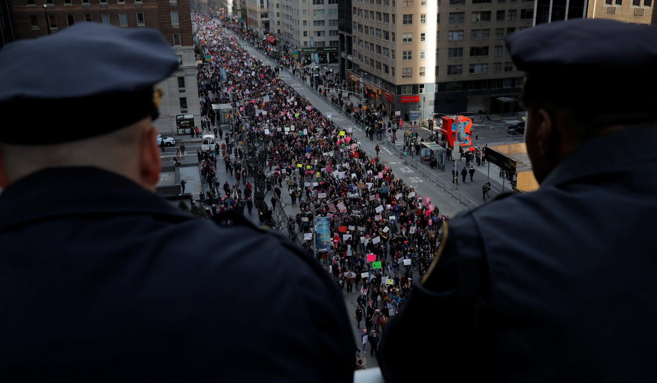 Members of the New York Police Department watch people walk down Sixth Avenue as they participate in the Women's March in Manhattan. Photo: Reuters