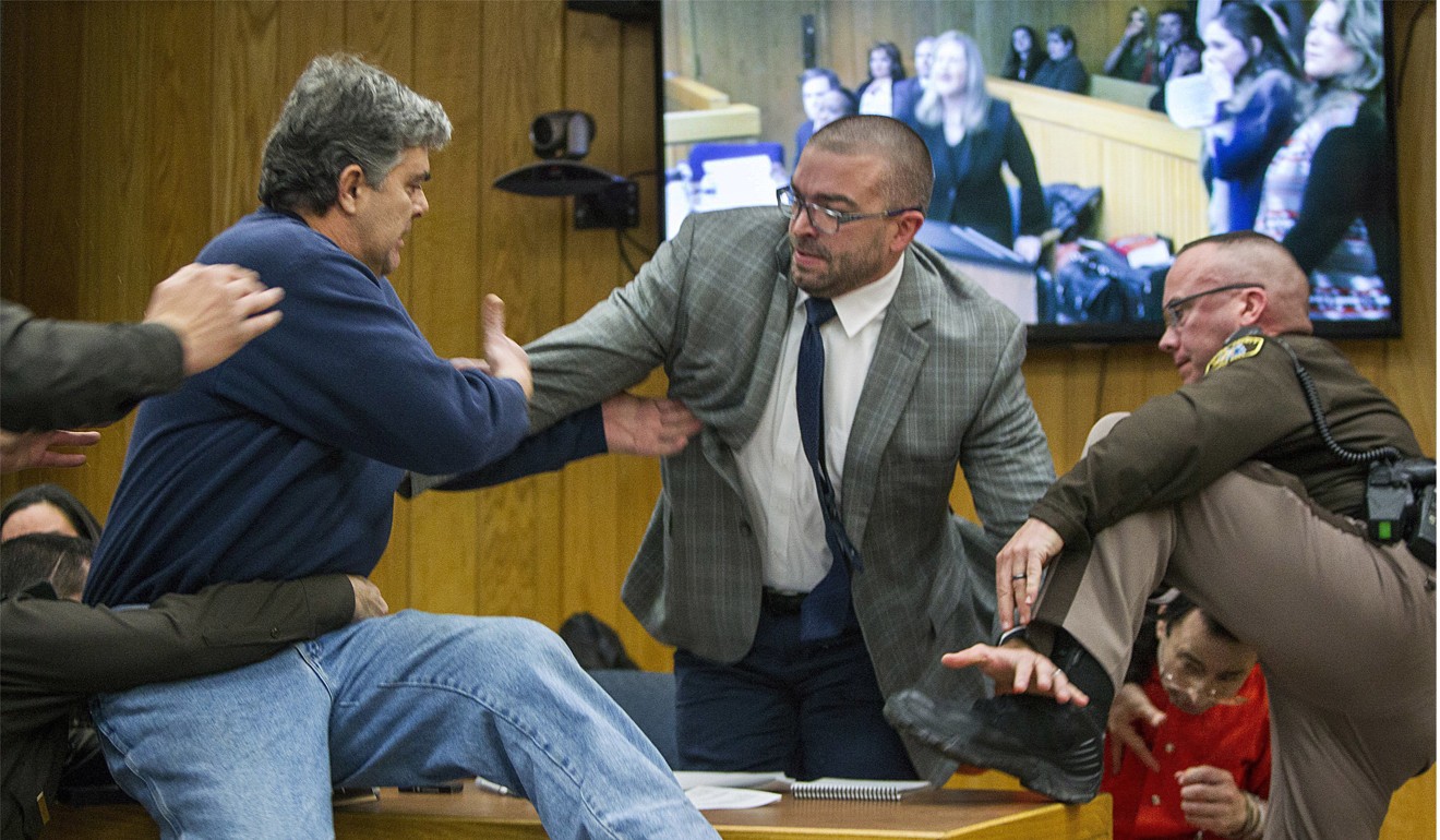 Randall Margraves (left) father of three victims of Larry Nassar, background right, lunges at Nassar in Eaton County Circuit Court in Charlotte, Michigan on February 2, 2018. Photo: The Grand Rapids Press via AP