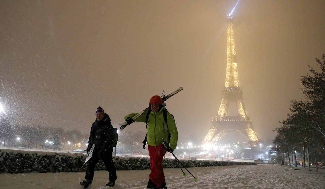 Men walk with skis on a snow-covered path near the Eiffel Tower in Paris on Tuesday. Photo: Reuters