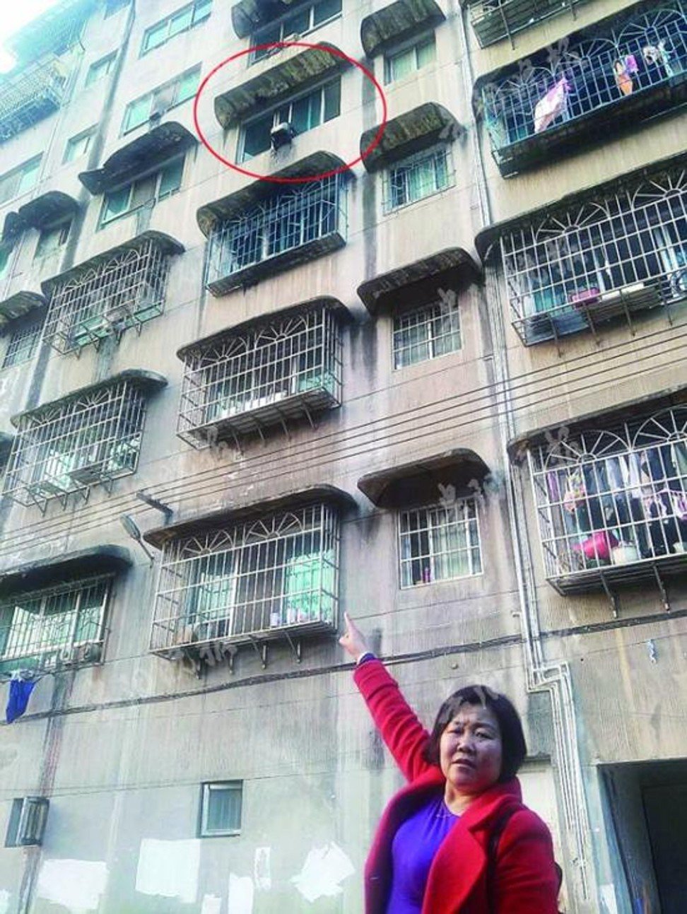 A woman points to the window from which the little girl fell. Photo: Sina