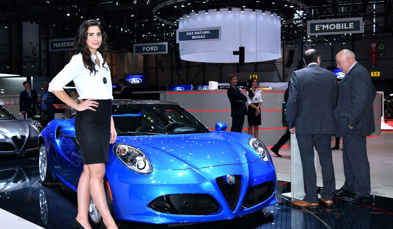 A hostess poses next to the new Alpha Romeo 4C Spider Italia at the Geneva International Motor Show. Photo: AFP
