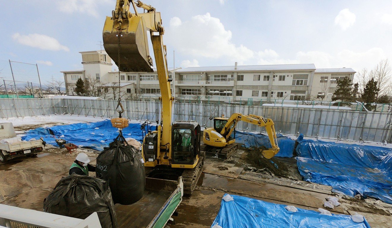 Workers retrieve bags of radioactive contaminated soil that had been stored underground at a junior high school playing field in Koriyama, Fukushima Prefecture. Photo: Kyodo