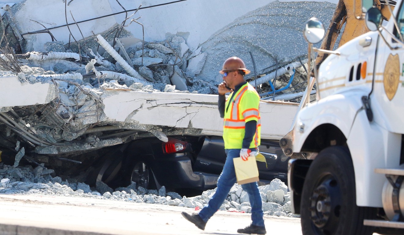 A worker walks past a car that was almost completely flattened under the collapsed bridge at Florida International University in Miami. Photo: Reuters