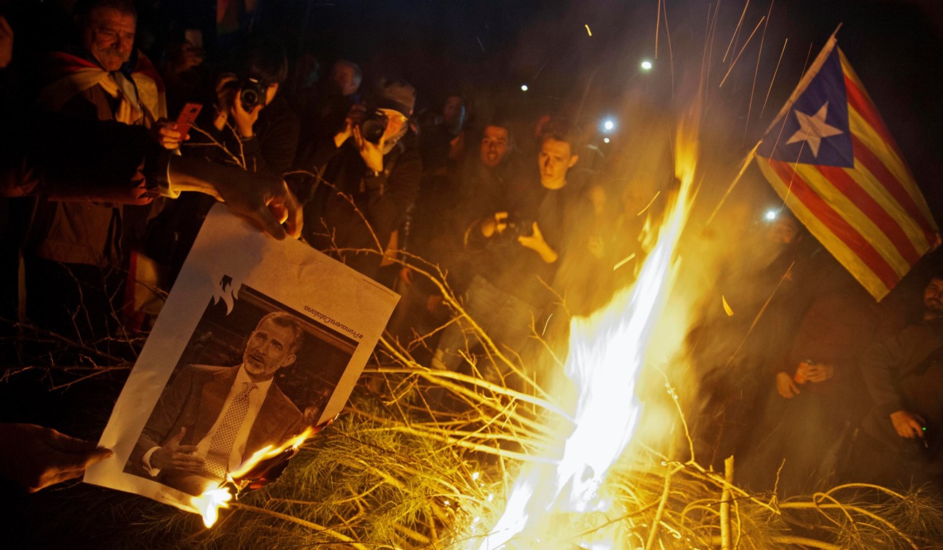 People burn images of Spain's King Felipe VI as they attend a protest against the detention of former Catalan leader Carles Puigdemont in Girona on Sunday. Photo: EPA
