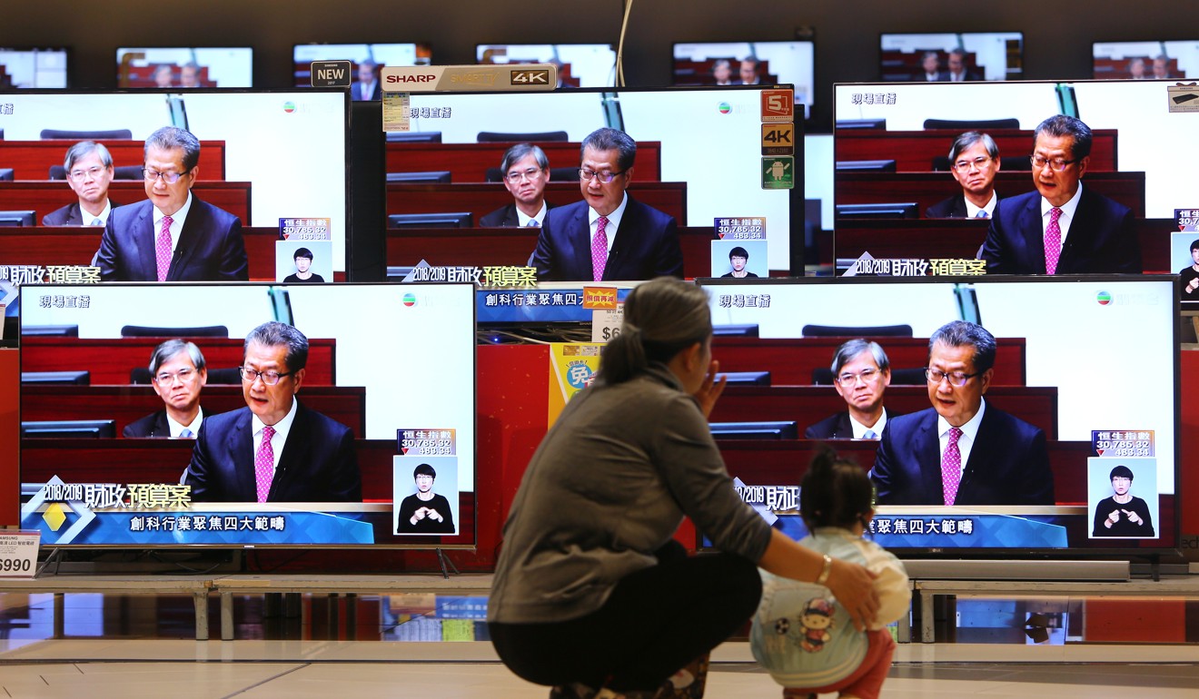 A woman and a child watch a live broadcast of Hong Kong Financial Secretary Paul Chan Mo-po delivering the 2018-2019 budget, which included a tax break for the middle class, in Kowloon Bay. Photo: Winson Wong