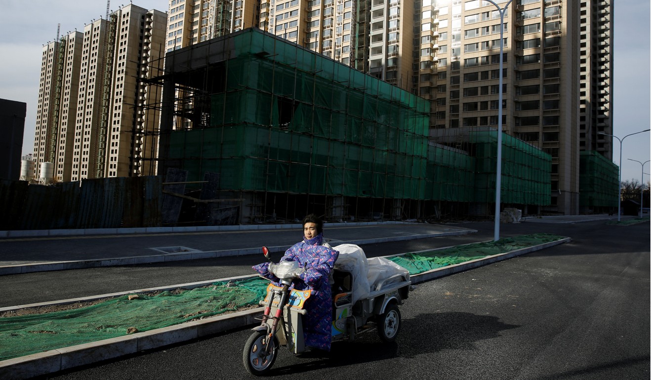 A man rides an electric tricycle past residential blocks under construction on the outskirts of Beijing. Photo: Reuters