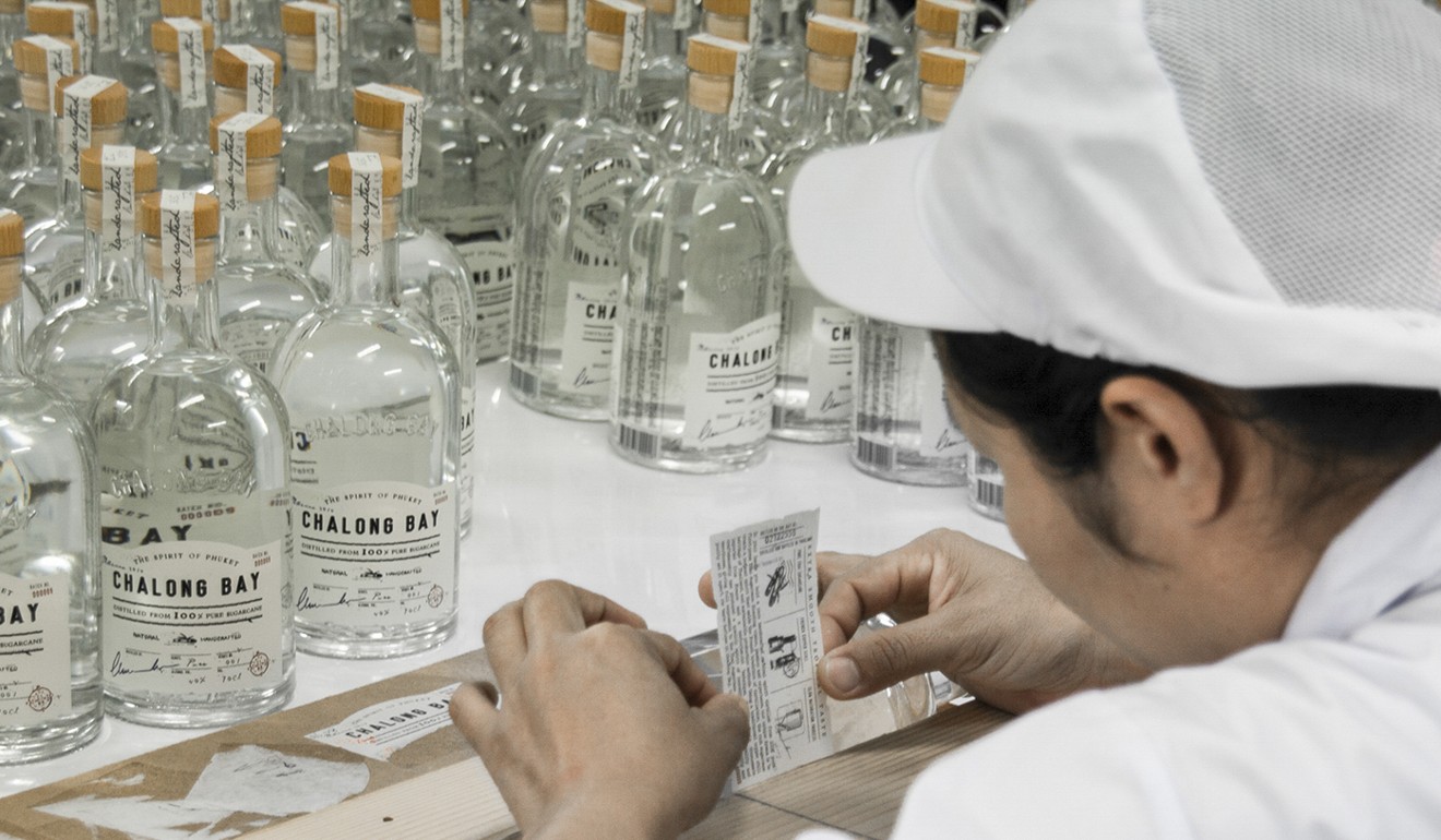 Staff individually label bottles at the Chalong Bay Rum factory.