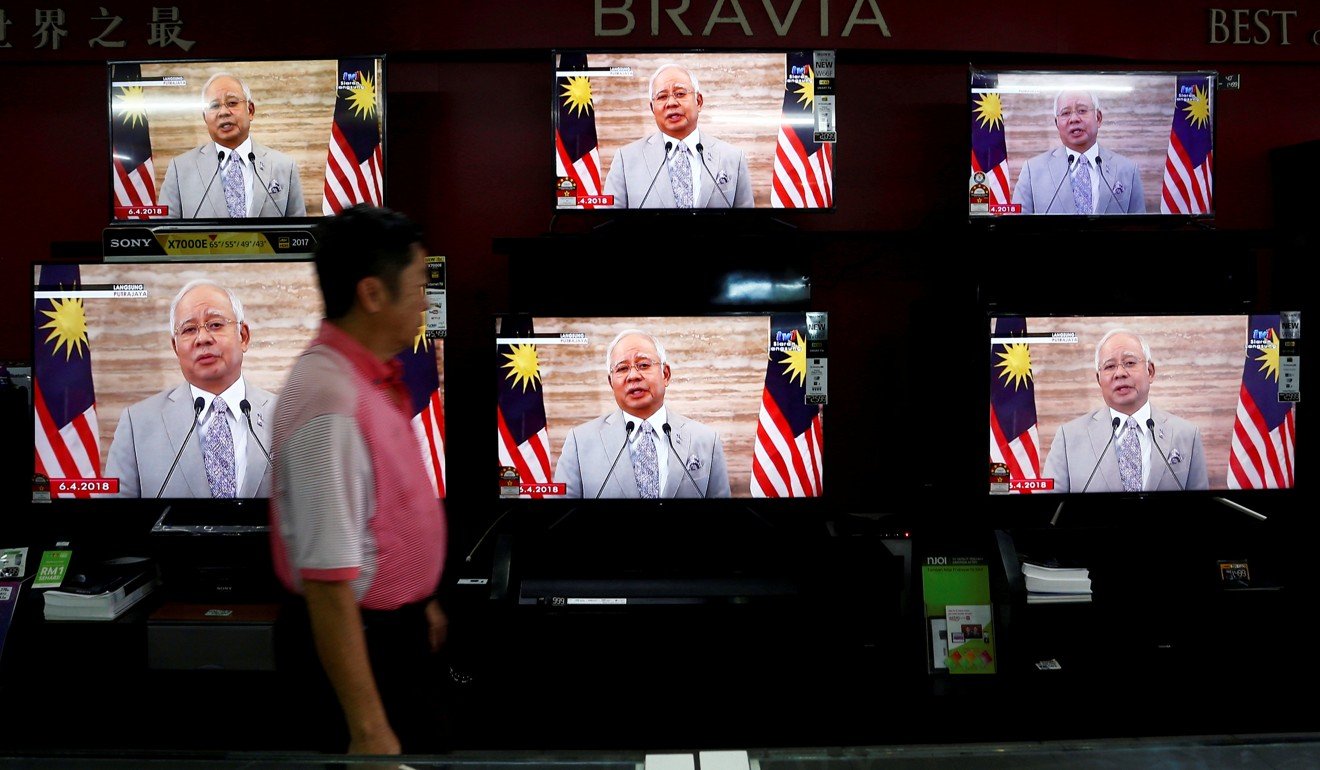 A man passes a live telecast of Malaysia's Prime Minister Najib Razak addressing the nation ahead of calling the May 9 election. Photo: Reuters