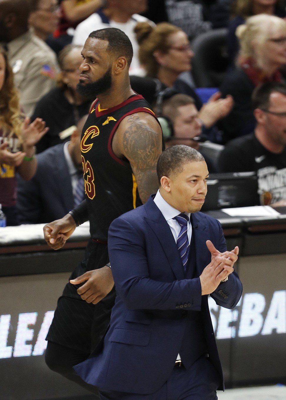 Cavaliers head coach Tyronn Lue walks on the court as LeBron James heads to the bench during the second half. Photo: EPA