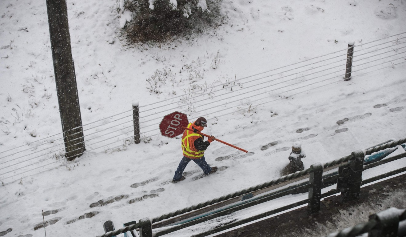 A construction worker carries a stop sign in the snow near the Brooklyn Bridge Park in New York City. Wage growth in the US, a key determinant of the degree of inflationary pressure, remains subdued for the time being. Photo: AFP 