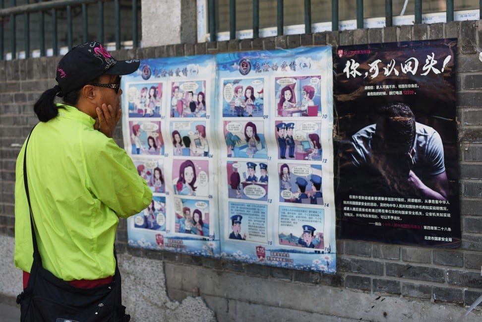 A woman looks at a propaganda cartoon warning local residents about foreign spies, in Beijing last year. Photo: AFP