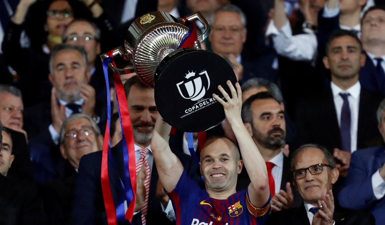 Barcelona's Andres Iniesta celebrates by lifting the trophy after the match as the King of Spain Felipe VI applauds.