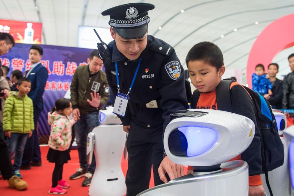 A police officer helps a child interact with one of the automated police robots, or robocops that patrol Shenzhen North railway station during the Spring Festival travel rush. Photo: AFP
