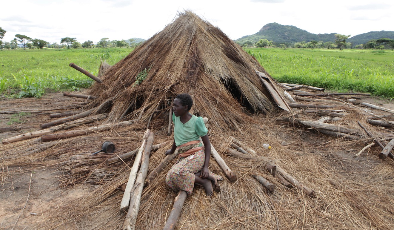 Florence Gurure sits next to her destroyed grass hut at Manzou Farm in Mazoe, north of Harare in Zimbabwe. It has been reported that police officers destroyed the thatch huts. The police told the source and other protesting tenants that the land was earmarked for the president’s wife, Grace Mugabe. Photo: AP