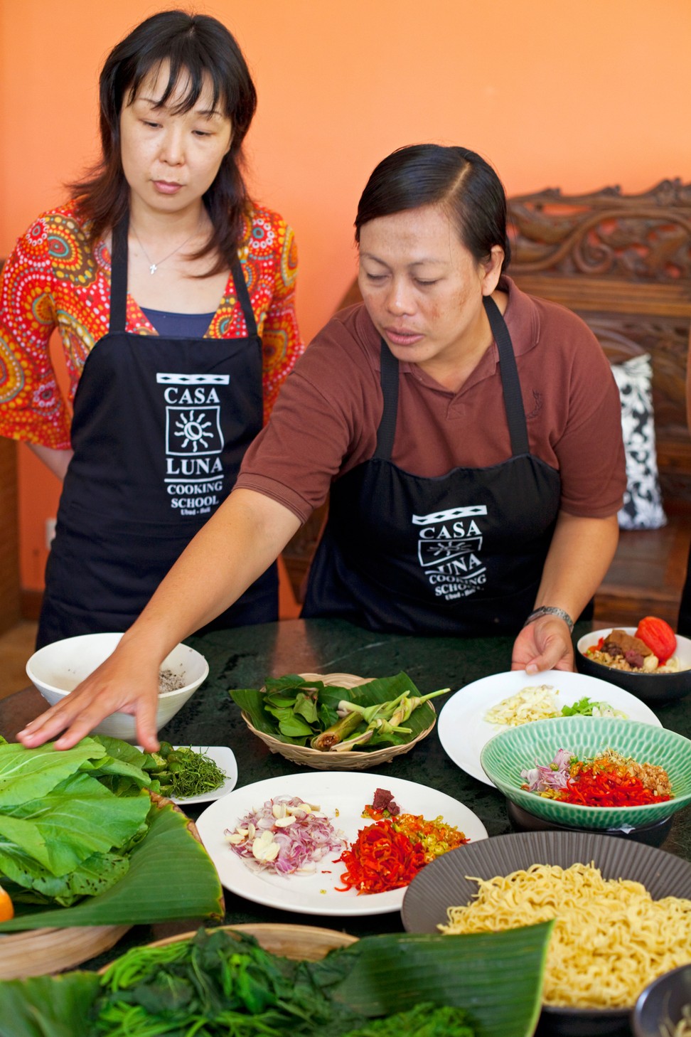 A young woman is shown how to cook traditional Balinese cuisine. Photo: Alamy