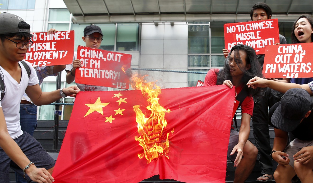 Protesters burn a Chinese flag during a protest against China's deployment of missiles on Philippine-claimed reefs. A group of left-wing activists disrupted a televised Independence Day speech by the Philippine president and called him a “traitor” amid criticism of his handling of territorial disputes with China. Photo: AP