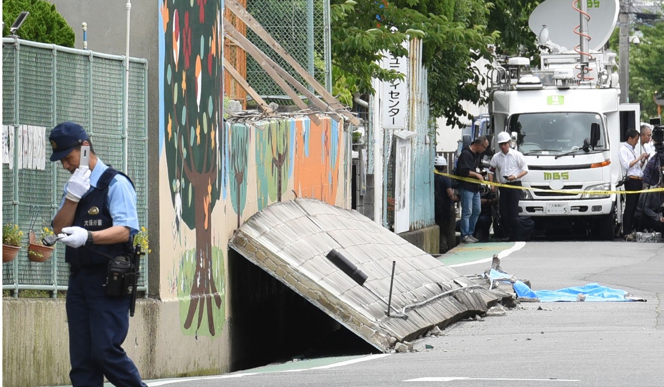 A policeman near a collapsed wall where a girl died following an earthquake in Takatsuki City, north of Osaka prefecture. Photo: AFP