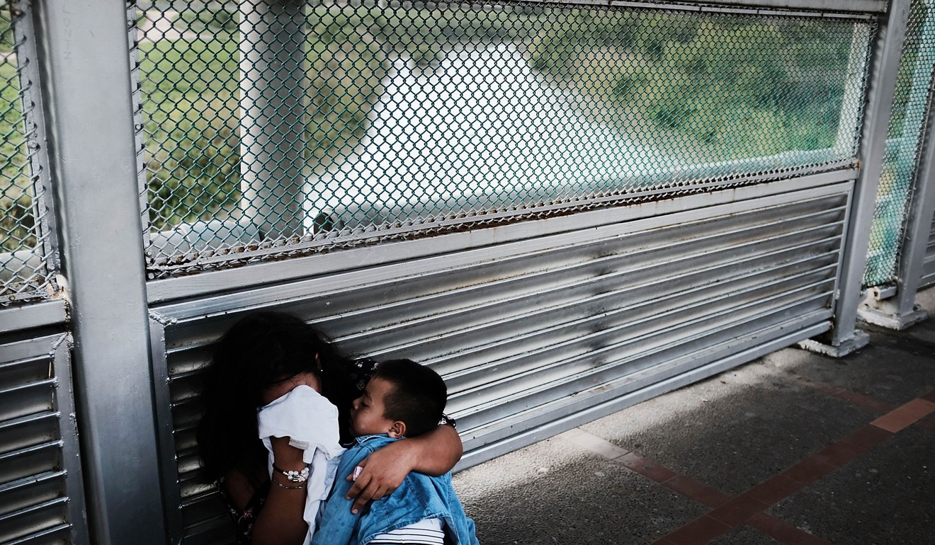 A crying Honduran woman and her child wait along the border bridge on Friday after being denied into the Texas city of Brownsville, which has become dependent on the daily crossing into and out of Mexico. Photo: Getty Images/AFP