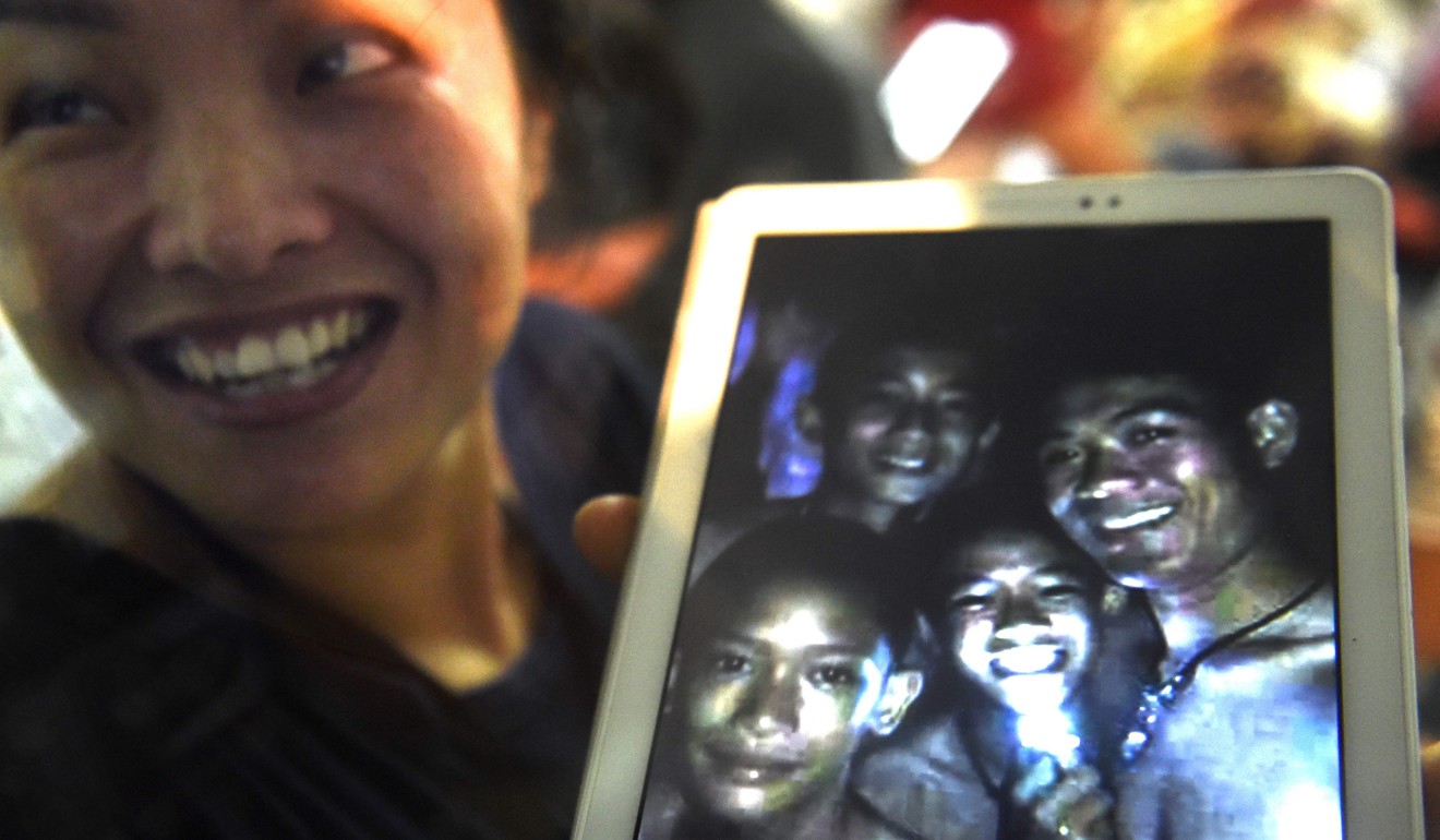 A family member shows a picture of three of the missing boys and their coach. Photo: AFP