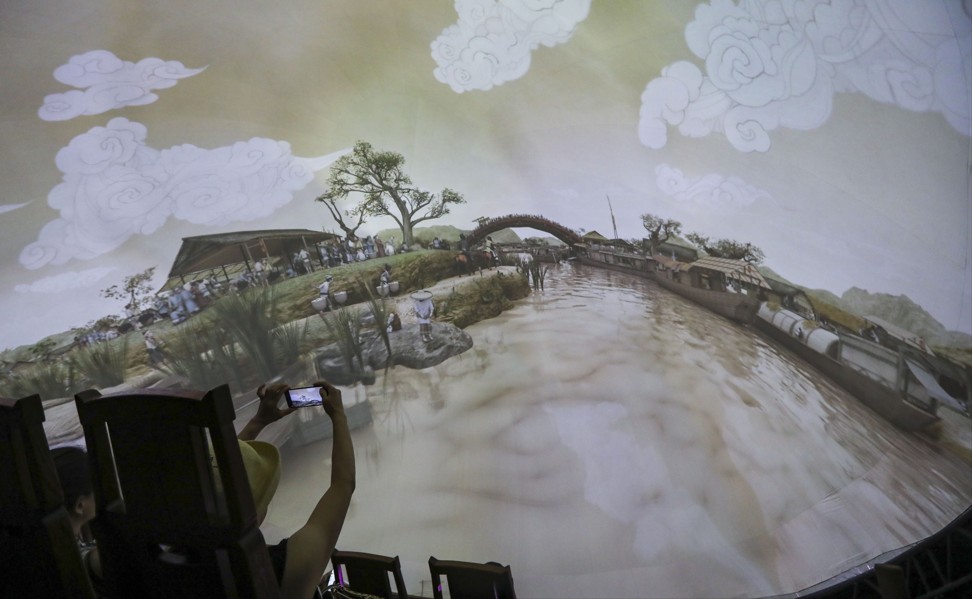 Visitors take a virtual boat ride down the river as part of an interactive digital display of the scroll painting Along the River During the Qingming Festival by 12th-century painter Zhang Zeduan. Photo: Simon Song