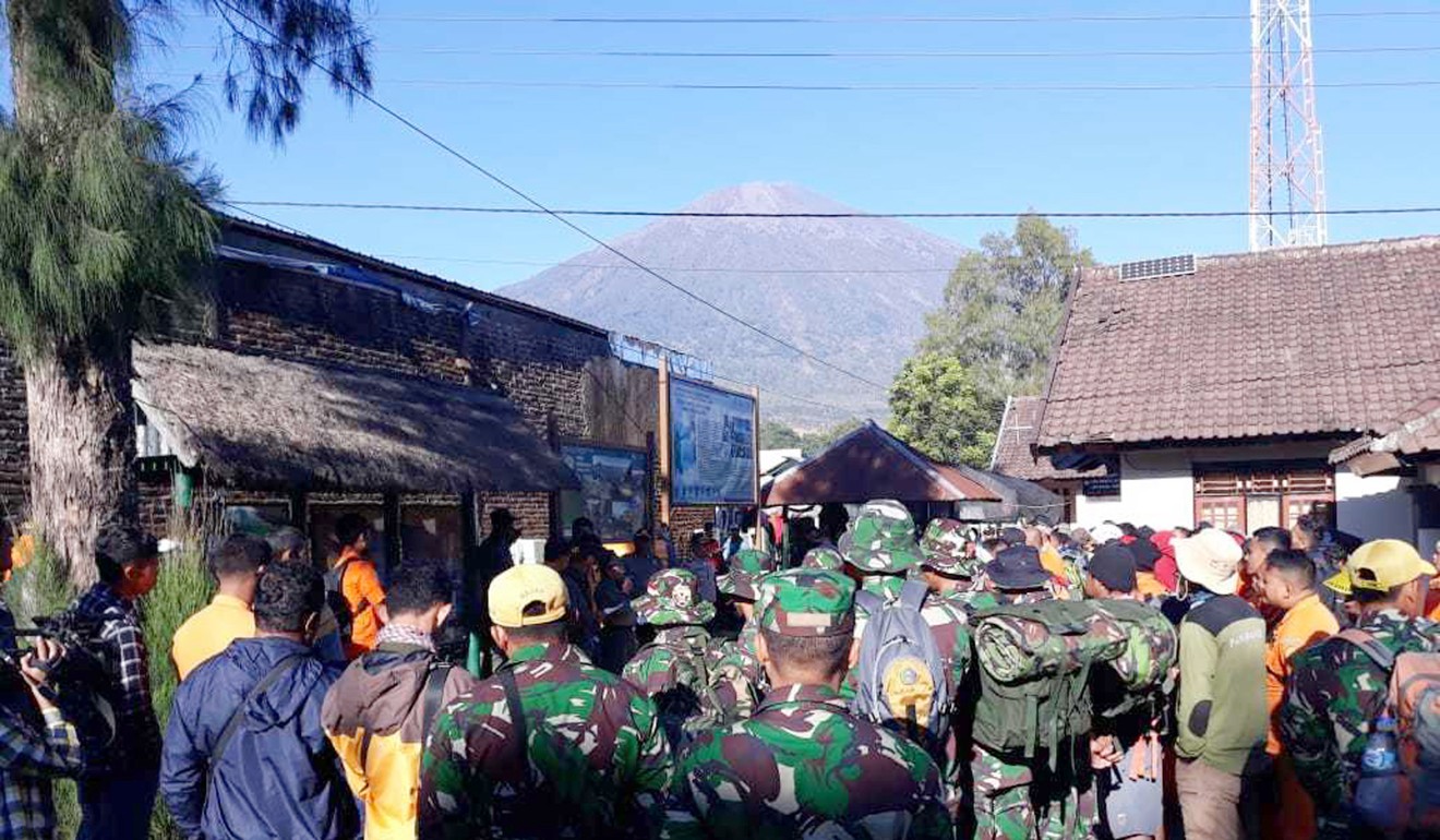 Indonesian soldiers prepare to evacuate tourists from Mount Rinjani, seen in the background, at Sembalun in East Lombok. Photo: AP