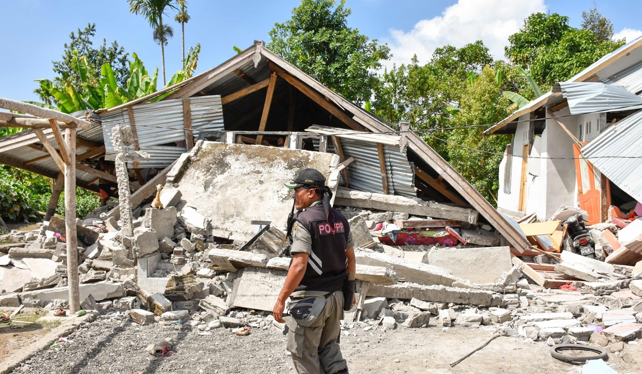 An Indonesian village security officer examines the remains of houses in Lombok. Photo: AFP