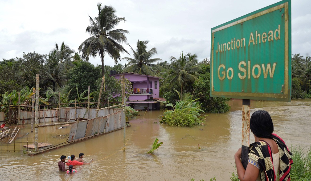 A woman watches people walking through flooded streets on the outskirts of Kozhikode district in Kerala, India on August 17, 2018. Photo: AFP