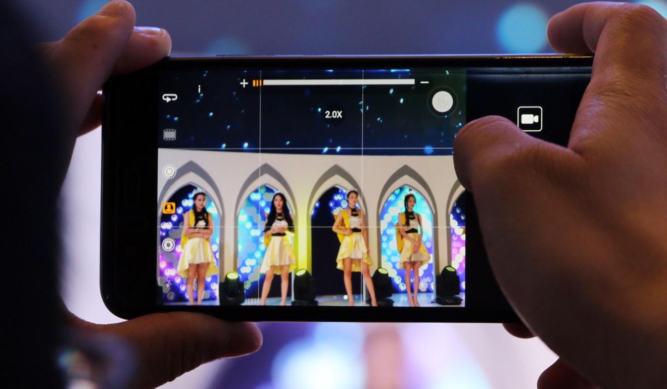 A male attendee takes video of showgirls at the booth of mobile games developer IGN. Photo: Zheping Huang