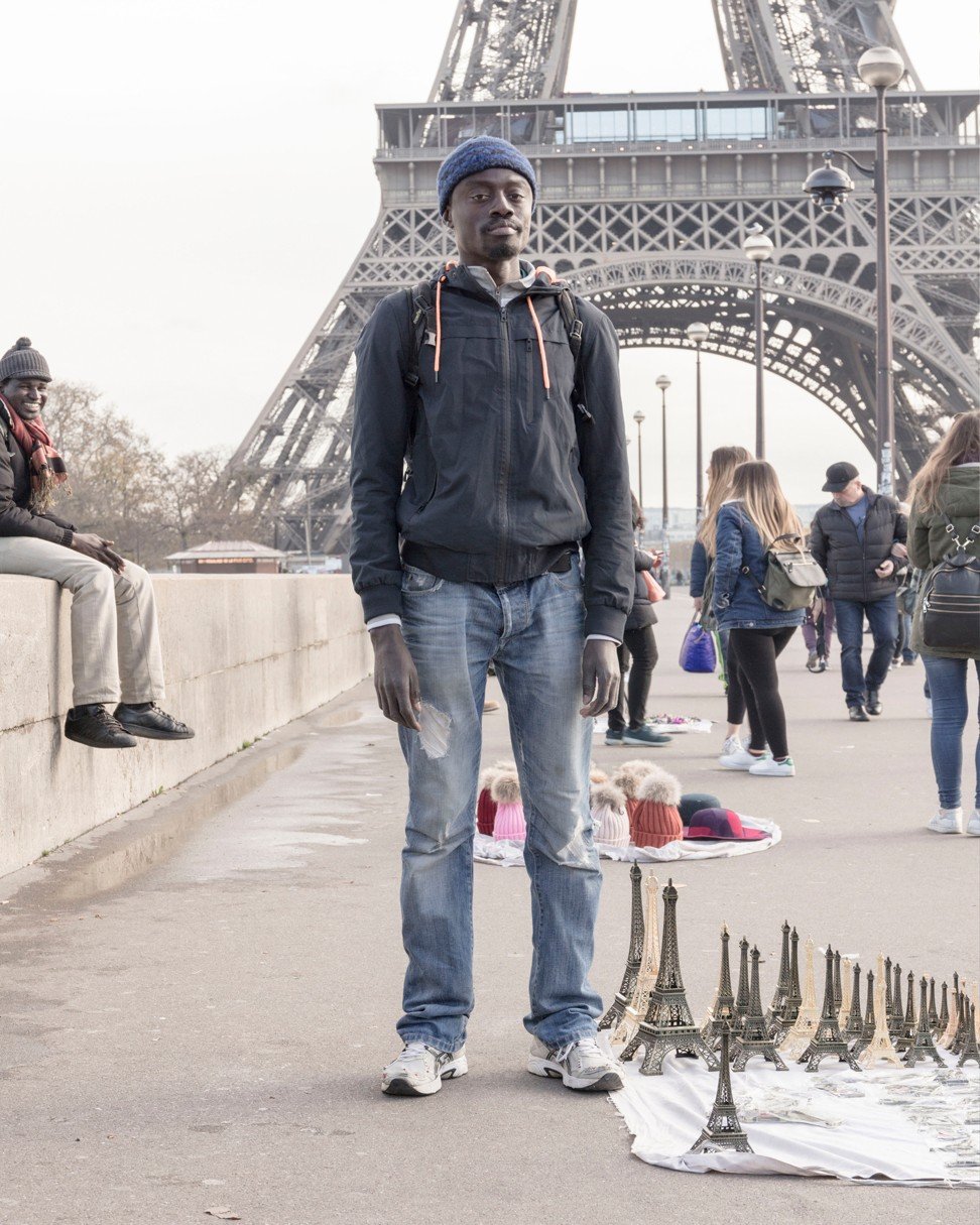 A man sells souvenirs in front of the Eiffel Tower in Paris. Photo: Francois Prost